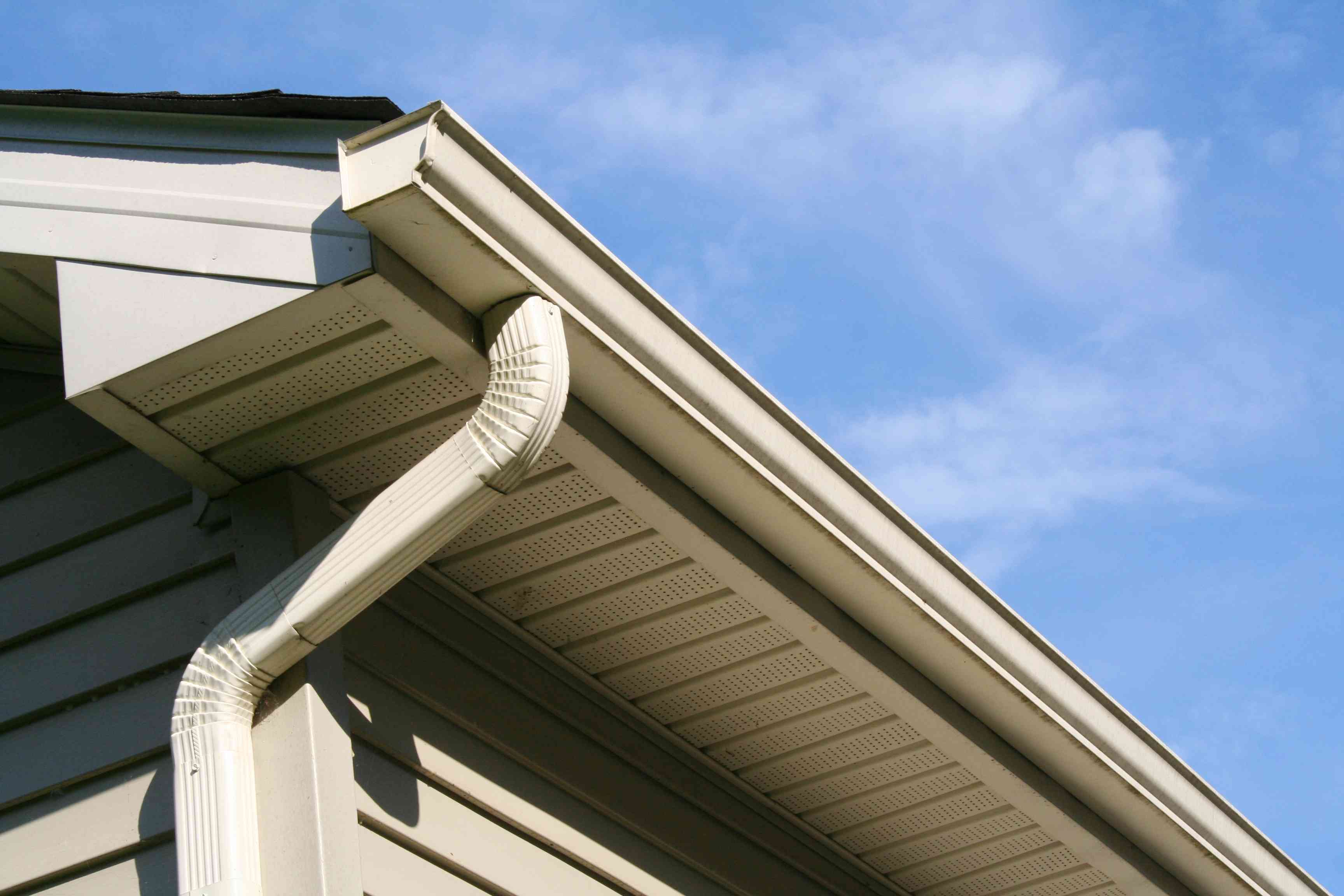Gutters along a home roofline against a blue sky